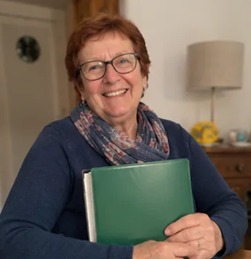 Christine F. serrant son classeur familial dans ses bras