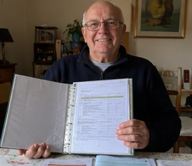 Jean-Pierre B. à sa table avec dossier rempli